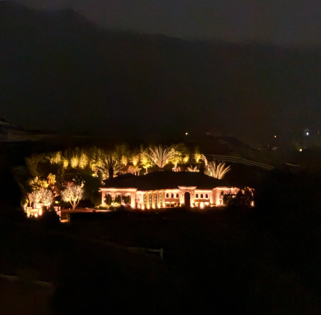 Luxury estate with landscape uplighting on palms and warm facade glow